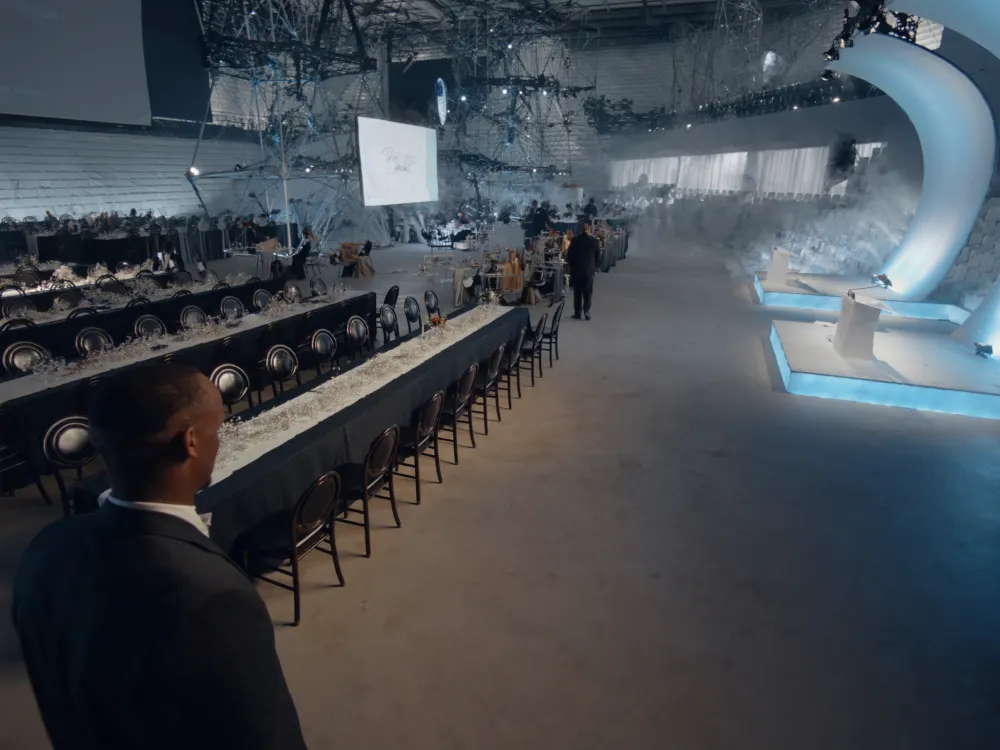 Salón preparado para un evento empresarial con escenario y luz fría