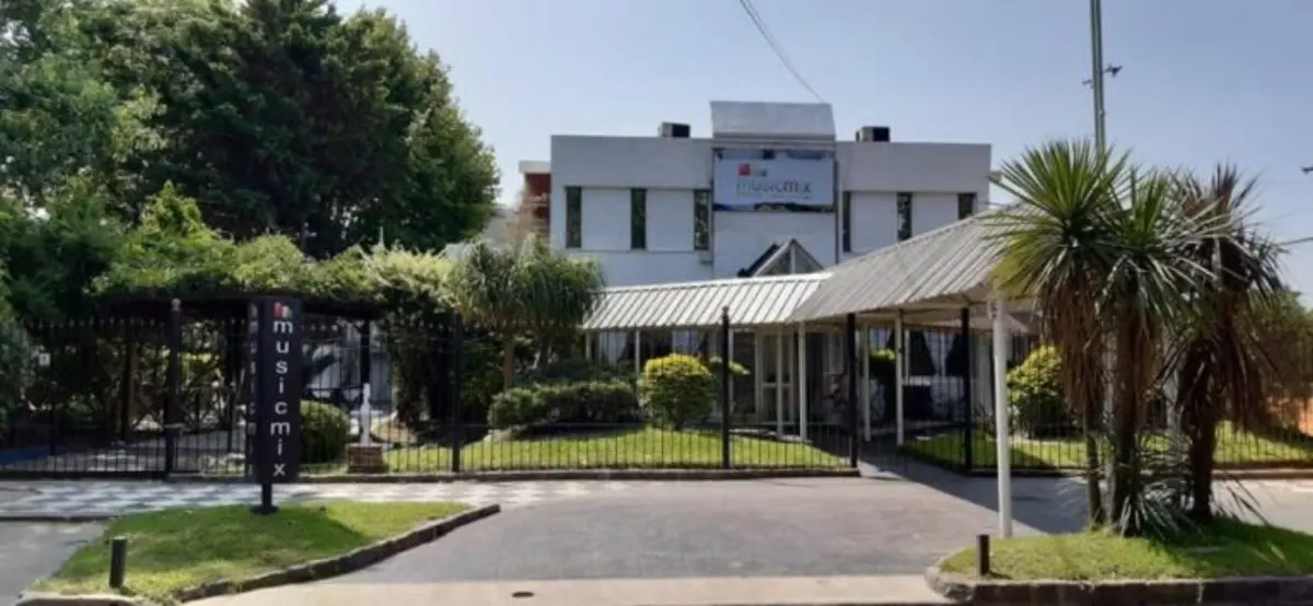 Frente del salón de día, con jardín, palmeras y galería de acceso